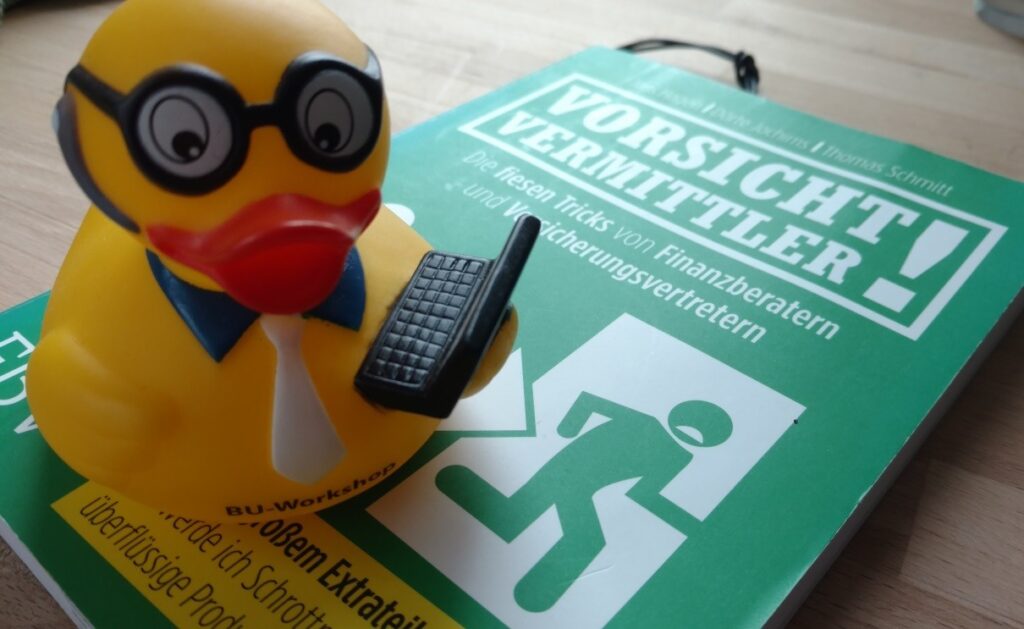 Ente mit Laptop auf dem Buch Vorsicht Vermittler